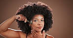 Beauty, face roller and serious with black woman in studio for cosmetics or dermatology routine. Aesthetic, facial and skincare with confident model on wall background for antiaging stone treatment