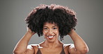 Afro, shake and beauty with face of black woman in studio for curly hair, textures and cosmetics. Volume, keratin and shine with person on gray background for growth, smile and natural transformation
