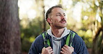 Man, walking and hiking with backpack in forest for adventure or outdoor journey in nature. Male person, hiker and trekking with bag or natural scenery for fitness, exercise or trip on trail or path