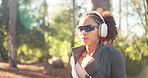 Woman, running and health with headphones in forest for spring jog, workout or outdoor exercise. Active, female person or runner with sunglasses for fitness, cardio or wellness in woods or nature