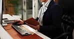 Hotel, schedule and typing with hands of concierge at welcome desk for check in or booking. Computer, keyboard and notebook with secretary in reception for accommodation, hospitality or service