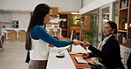 Hotel, reception and couple with passport for check in, reservation and honeymoon accommodation. Hospitality industry, concierge service and people with arrival for holiday booking and confirmation