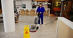 Janitor, man and office with caution sign, hygiene service and wet floor for disinfection. Sanitation, safety and warning for risk, management and cleaner with tile polishing equipment or maintenance
