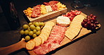 Cheese board, cold meat and grapes with crackers for snack, food or charcuterie for catering. Healthy, fruit and gourmet selection with fresh ingredients on wooden surface for nutrition or meal