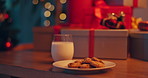 Gifts, milk and cookies on table for christmas eve with celebration, tradition or holiday season. Presents, sweet treat and biscuits with dairy drink for festive dessert with santa claus in home.