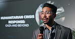 Man, presenter and speech with mic for human rights, activism and convention for global conflict. Person, speaker and public speaking at conference for world peace, war and problem solving by screen