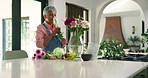Arrangement, aroma and mature woman with flowers in vase for growth, natural bloom and plant care. Happy, home and person with bouquet, floral and blossom for display, decoration and aesthetic