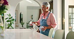 Mature woman, cleaning and detergent with spray bottle on table for housekeeping or chores at home. Female person, cloth and wiping surface with chemical liquid for bacteria or germ removal at house