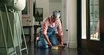 Mature woman, cleaning and sweeping floor in house or apartment for career, maintenance or housekeeping. Female person, worker and dirt or mess with cleaner service, domestic and home improvement