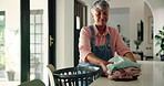 Mature woman, cleaning and packing laundry with basket for housekeeping or chores at home. Female person, maid or cleaner with smile for fabric, clothing hygiene or garment disinfection at house
