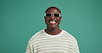 Happy, black man and fashion with sunglasses in studio for accessory or swah on a green background. Portrait, male person or African model with smile or shades for stylish eyewear on mockup space