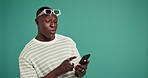 Dating app, phone and reaction with black man on green background for search for social media match. Mobile, smile and swipe with happy African person in studio for profile browsing on internet