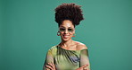 Arms crossed, smile and sunglasses with black woman on green background for fashion or style. Afro, confident and shades with happy African person isolated in studio to model trendy clothing outfit
