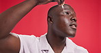 Black man, oil dropper and skincare in studio for dermatology, glow and beauty by red background. African person, serum or hyaluronic acid with cosmetics, grooming and application for facial product