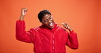 Celebration, fist pump and success with black woman on wall background for dance or motivation. Energy, excitement and victory with happy African person in orange studio as winner of competition