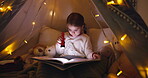 Reading, book and child with torch, home or learning with novel on bed, hobby and knowledge in tent. Night, growth and development of girl with story, literature or kid with tech for fiction in house