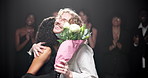 Flowers, hug and smile of fashion designer people on stage at showcase with thank you for applause. Bouquet, event and runway with style team at clothes presentation for creative career or gratitude