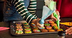 Hands, child and mother piping of cookies for decoration, icing skills and sweet treats in kitchen. Kid, woman and help with baking, festive preparation and santa snacks for bonding together at house