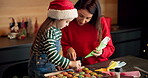 Decorating, biscuits and mom with child in kitchen, learn or cream for dessert on Christmas in home. Teaching, daughter and woman with sprinkles for cookies, baking and snack for festival in house