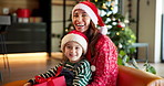 Happy mom, face and child on sofa for christmas holiday, festive season or celebration at home. Portrait, mother or kid with smile or hat for santa weekend, december joy or new year together at house
