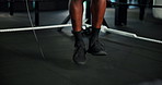 Feet, person and skipping rope at gym for fitness, warm up routine and preparation for boxing match. Legs, boxer and jump with equipment for getting ready, endurance training and workout of challenge