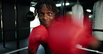 Boxing, fitness and face of black man with gloves in gym with challenge, self defense or training. POV, knockout and portrait of male boxer with power punching practice for workout in sports center.