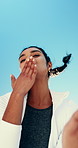 Outdoor, blow and kiss with face of woman for flirting, affection and expression for love. Portrait, person and mockup space with blue sky for care gesture, romance emoji and laughing with silly pout