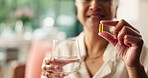Hands, capsule and glass for medicine in home, health and wellness with supplements in living room. Mature person, water and pills for omega 3, benefits and pharmaceutical product in morning at house