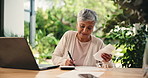Senior woman, budget and writing on document, debt free and happy for savings on laptop. Receipt, counting and person in retirement for finance, investment and positive credit score in home backyard