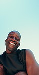 Outdoor, black man and exercise break with face for fitness, running challenge and arms crossed. Blue sky space, male person and runner with confidence for inspection, laugh and happy from below