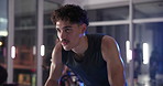 Cycling class, sweat and man in gym for spinning workout, health or leg muscle training at night. Fitness, activity and male athlete on bicycle machine for cardio exercise with group in sports center
