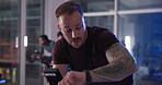Fitness, spin class and watch with man on bike in gym for cardiovascular training at night. Exercise, performance and time with athlete person cycling in health club for challenge or intense workout