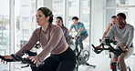 Fitness, indoor cycling and woman exercise with instructor for cardio, talk or endurance challenge. Stationary bike, group training and class for body health, workout or sports with energy in gym