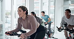 Fitness, class and woman on stationary bike with coach for cardio, talk or motivation. Indoor cycling, training and happy group exercise for body health, workout challenge or sports for energy in gym