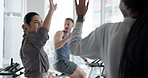 Happy people, cycling or fitness with high five for workout, success or spin class together at gym. Woman, group or applause with team in cardio exercise on stationary bicycle for health and wellness