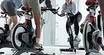 Legs, people and fitness with bike at gym for exercise, cardio training and cycling challenge. Group, coach and energy with bicycle machine, endurance workout and intense performance at spin class
