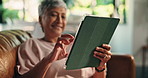 Senior woman, hands and tablet on sofa for playing online bingo, gambling app or internet surfing. Retirement, person or relax with digital tech in home for gaming site, streaming service or research