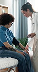 Woman, doctor and patient with blood pressure, exam and assessment for hypertension at hospital. People, medical equipment and consulting with help, test or monitor with healthcare services at clinic