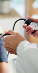 Hands, doctor and person with blood pressure, pump and assessment for hypertension at hospital. People, medical equipment and support for wellness, exam or monitor with service for patient at clinic