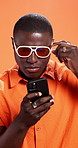 Black man, phone and sunglasses in studio, search or online shopping for fashion by background. African person, smartphone and trendy style with clothes, mobile app and thinking with scroll for deal