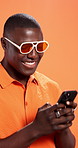 Black man, phone and sunglasses in studio, texting or happy for contact with fashion by background. African person, smartphone and smile with clothes, mobile app and social media with scroll on web