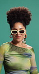 Face, dancing and woman in studio, smile and celebration on green background. Portrait, happy person and model with energy, movement and sunglasses with fashion, stylish clothes and confidence