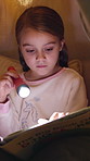 Girl, kid and reading book with flashlight at night for fairy tale or bedtime story at home. Child, relax and late evening with light or torch for novel, imagination or literature in bedroom at house