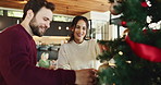 Happy couple, christmas or tree with decor for december or christian holiday together at home. Man, woman or lovers with smile, bauble or hanging with ornaments for celebration or festive decorations