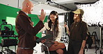 High five, makeup and styling with director on set for production or videography success. Behind the scenes, green screen and thumbs up with man speaking to talent in studio for film satisfaction