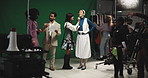 Woman, actress and makeup artist on film set for face, director and cameraman for production. People, cosmetics and touchup with green screen, cinematography or recording equipment at movie studio