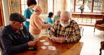Senior men, friends and playing cards in retirement, talk and contest with deal, challenge or bet. Elderly people, together and relax with game, competition and conversation in hall for bridge
