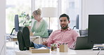 Businessman winking and flirting at a colleague in the office. Asian professional sitting with his feet up on his desk and looking contemplative. Sexual harassment in the workplace by male coworkers