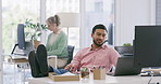 Businessman winking and flirting at a colleague in the office. Asian professional sitting with his feet up on his desk and looking contemplative. Sexual harassment in the workplace by male coworkers