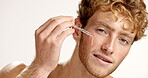 Serum, beauty and face of man in studio for vitamin c, skincare and facial treatment. Essential oil, cosmetics and self care with person and dropper on white background for dermatology and glow